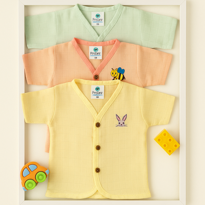 Three baby cardigans in green, orange, and yellow with cartoon characters on a light beige background.
