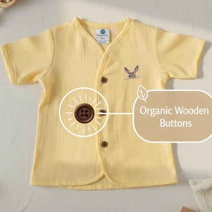 Yellow baby shirt with organic wooden buttons on a light background