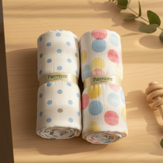 Two rolled-up swaddles with colorful polka dots on a wooden surface.