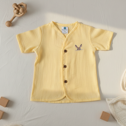 Yellow baby shirt with buttons on a light gray background