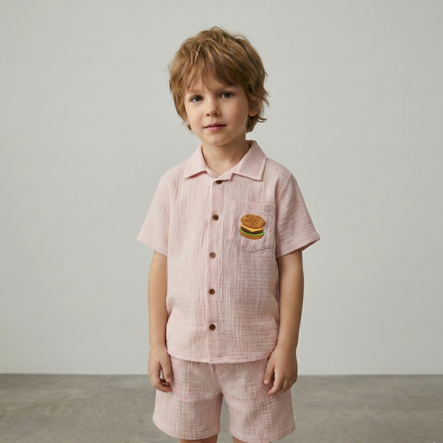 Child wearing a pink checkered outfit with a hamburger design on a plain background