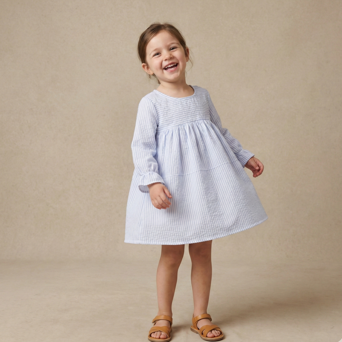 Young girl wearing a light blue dress against a beige background
