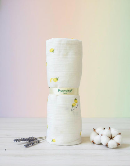 Stack of white fabric with a yellow pattern on a light wooden surface with a soft pastel background