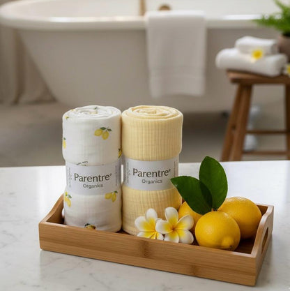 Two rolls of Parentre organic towels on a tray with lemons and flowers in a bathroom setting.