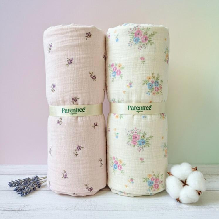 Two rolled-up baby blankets with floral patterns and 'ParenTree' branding on a light wooden surface.